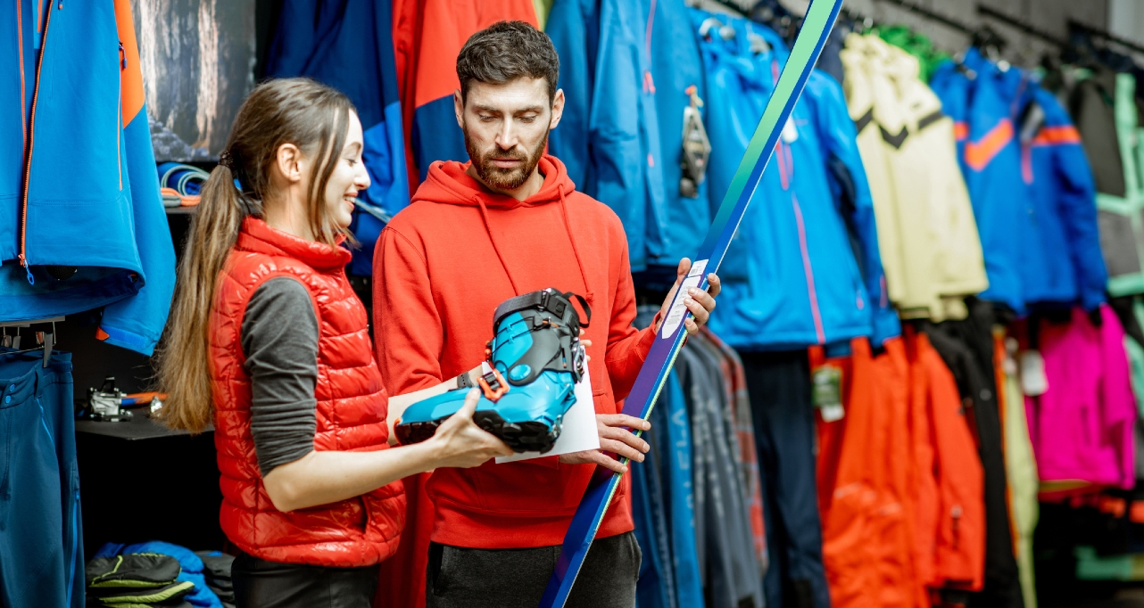 Man and woman choosing skiing equipment in the shop